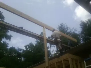 Carpenter setting a ridge beam over a new addition frame — Ice Dam Removal by Roofing Brothers in Alger