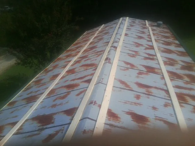 Rusted metal roof panels with new wood purlins before replacement — Storm Damage Roof Repair in Alger by Roofing Brothers