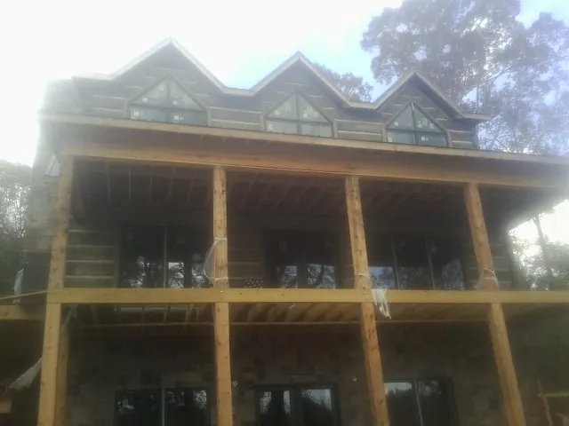 Dormers and porch framing on a large log home under construction — Roof Coating work by our crew in Alger