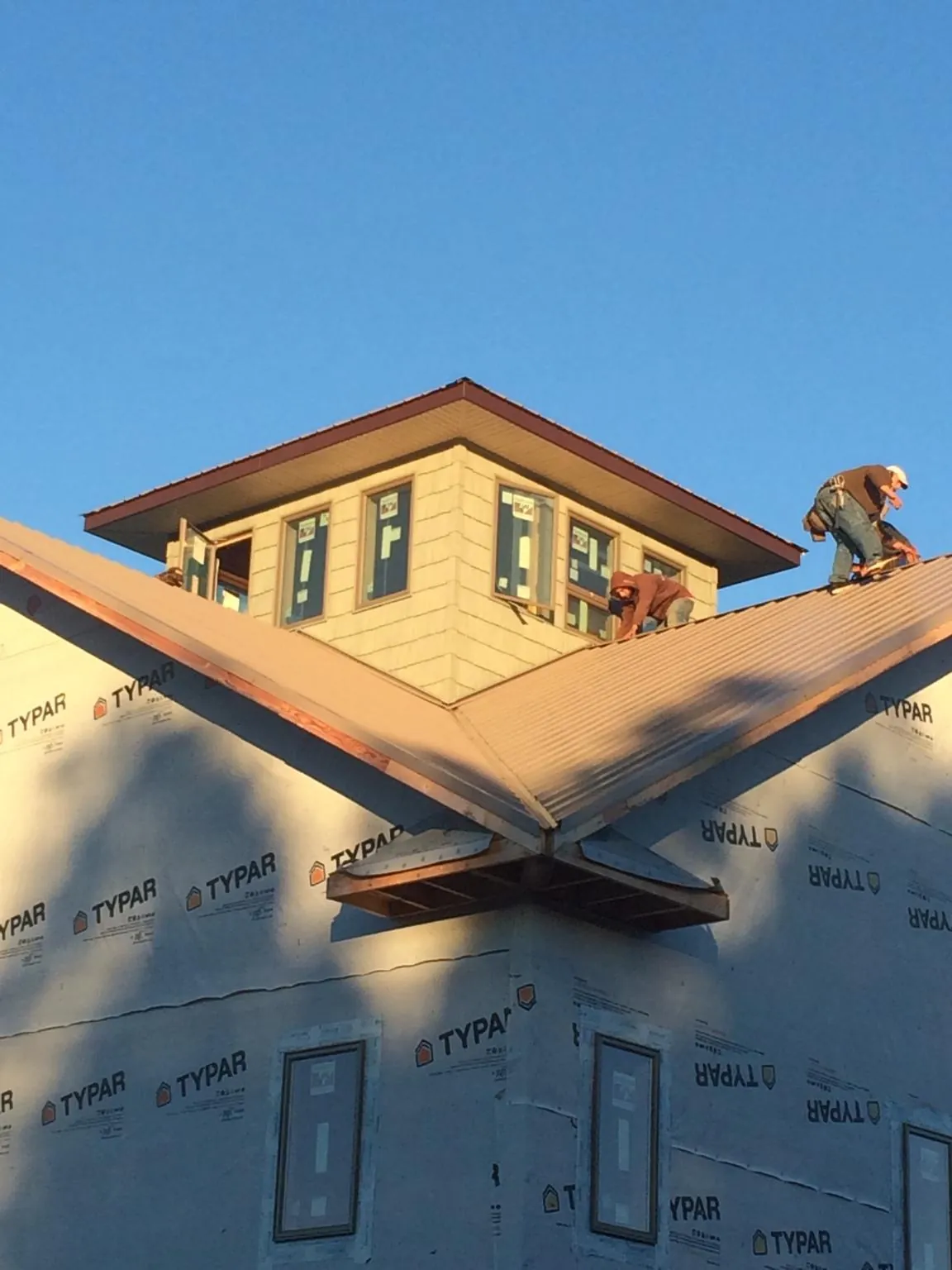 Roofers working around a rooftop cupola on a new metal roof at sunset — Roof Waterproofing in Alger by Roofing Brothers